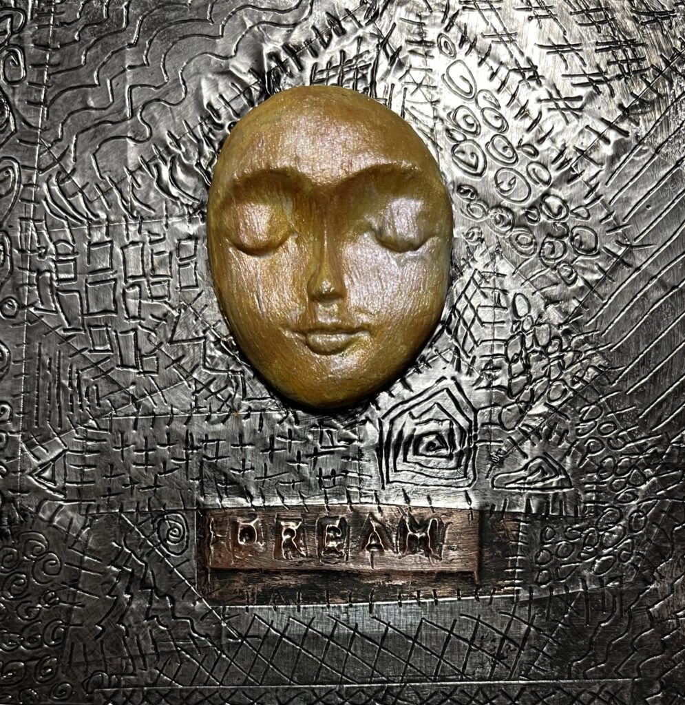 Artwork on engraved metal tape featuring a serene golden face and the word "DREAM"